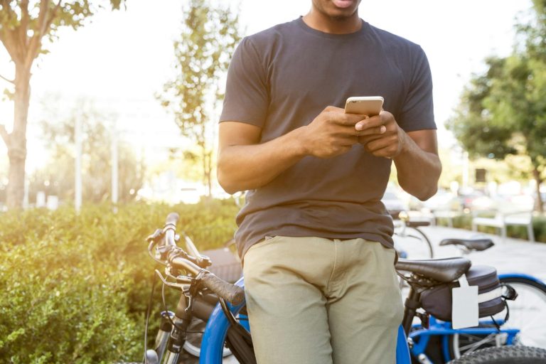 person leaning on bike while holding smartphone